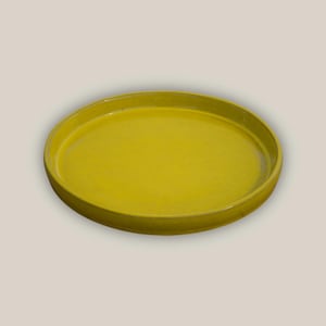 May include: A round, yellow ceramic tray with a slightly raised edge. The tray has a smooth, glossy finish and a bright, sunny color. This decorative tray is suitable for serving food or displaying items.