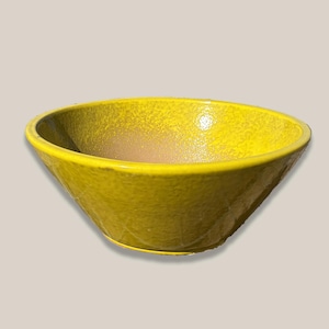 May include: A bright yellow ceramic bowl with a textured surface. The bowl has a wide, rounded rim and tapers to a narrower base. The interior has a lighter yellow hue.
