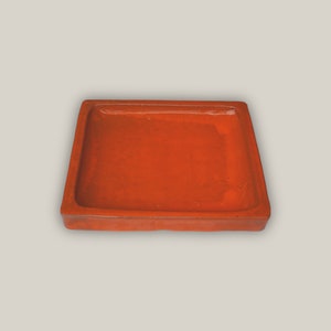 May include: A square, terracotta-colored tray with a smooth, glossy finish. The tray is perfect for serving snacks or holding small items.