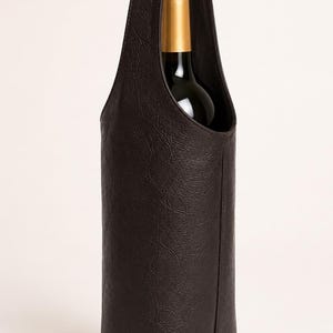 May include: A dark brown textured wine bottle carrier with a single integrated handle. The carrier features a vertical seam down the front and holds a wine bottle with a gold-coloured foil neck and a dark glass body, partially visible at the top.