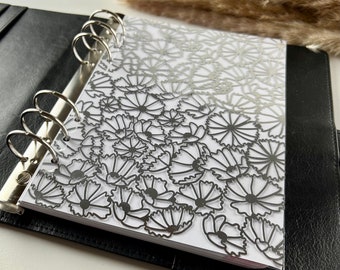May include: A black binder with silver rings and a clear plastic insert with a silver floral design.