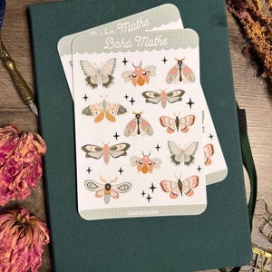 Könnte beinhalten: Ein weißer Aufkleberbogen mit verschiedenen Motten- und Schmetterlingsillustrationen in Rosa-, Orange- und Grautönen, akzentuiert durch kleine schwarze Sterne. Der Text "Boha Maths" steht oben und "danicacristine" unten auf dem Bogen.
