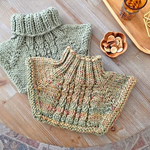 Può includere: Due scaldacollo lavorati a mano a maglia in tonalità di verde e filato variegato. Gli scaldacollo presentano un colletto a coste e un motivo a punto strutturato. Uno è verde chiaro unito, l'altro ha un mix di verde, arancione e rosa.