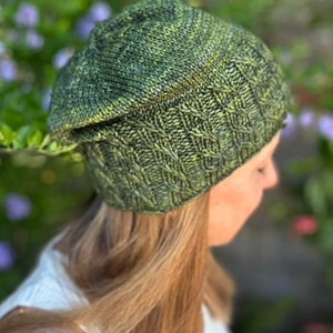 May include: A green and black knit beanie with a cable knit pattern. The beanie is slouchy and has a folded brim.