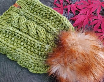May include: A green knitted hat with a cable knit pattern and a large fluffy orange pom pom.