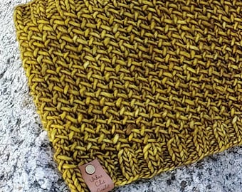May include: A mustard yellow knitted scarf with a brown leather tag that says "Urban Chic Crochet".