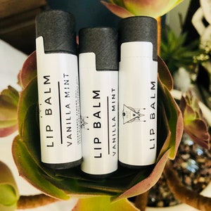 May include: Three lip balm tubes with black lids and white labels. The labels say "Lip Balm" and "Vanilla Mint".
