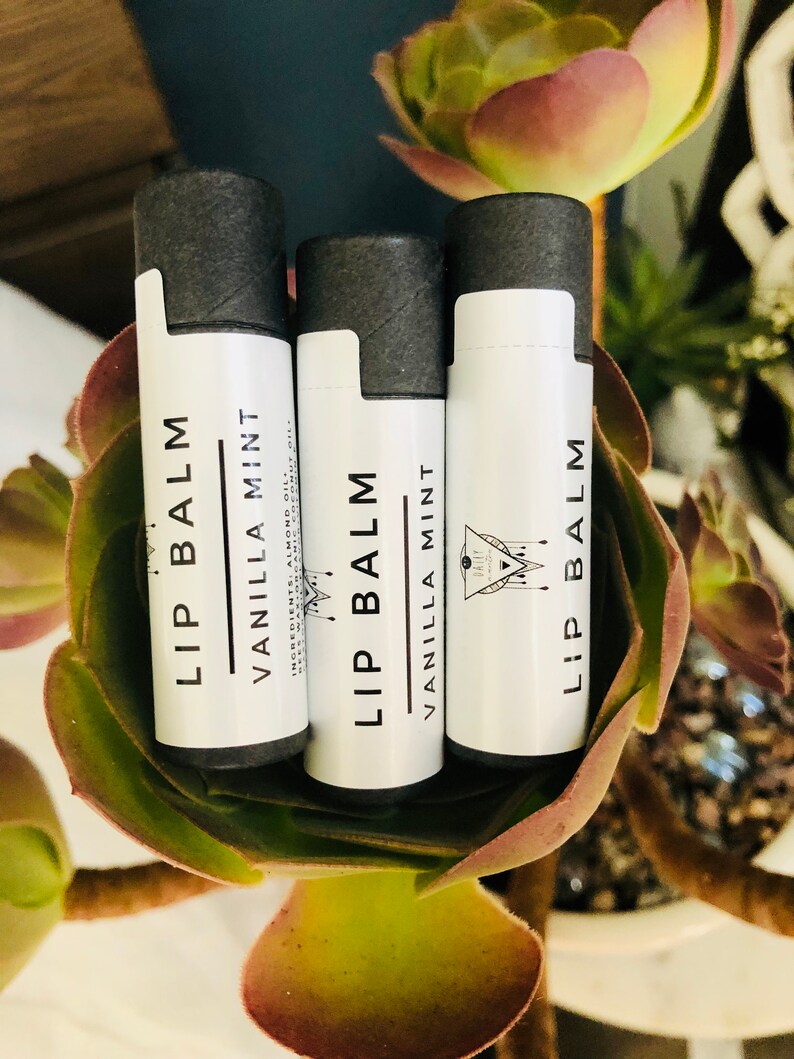 May include: Three lip balm tubes with black lids and white labels. The labels say "Lip Balm" and "Vanilla Mint".