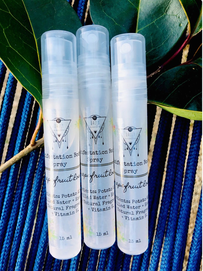 K&ouml;nnte beinhalten: Drei durchsichtige Plastikflaschen mit wei&szlig;en Spr&uuml;hk&ouml;pfen. Jede Flasche ist mit "Daily Manifestation Body Spray" und "Grapefruit Love" beschriftet. Die Flaschen sind jeweils 15 ml gro&szlig;.