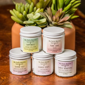 May include: Five white jars of organic body butter with pink labels and white lids. The labels have the text "My Daily Mantra" and the name of each scent: "Happiness", "Pure Love", "Sacred Self", "Kindred Spirits", and "Simply Beautiful".