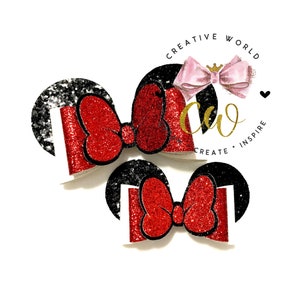Pode incluir: Duas orelhas de Minnie Mouse de glitter vermelho com orelhas de glitter preto. As orelhas estão sobre um fundo branco.