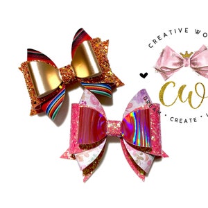 May include: Two handmade hair bows, one with a red, white, and blue striped pattern and gold glitter, and the other with a pink and iridescent glitter pattern. The bows are on a white background with a logo that says "Creative World" and "Dream, Create, Inspire".