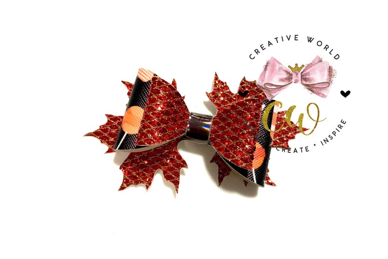 May include: A red and black glitter bow with a maple leaf design. The bow is tied with a black ribbon and has a gold glitter accent.