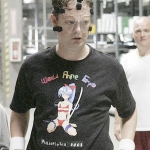 May include: A person wearing a black t-shirt with a colorful graphic of an anime character. The shirt says "World Anime Expo" and "Philadelphia, 2002".