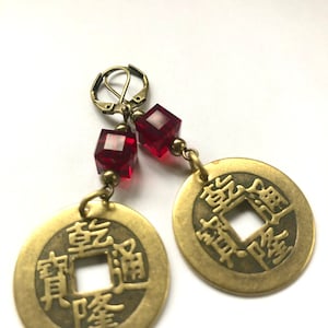May include: Gold tone earrings with red crystal beads and Chinese coin charms. The coins feature Chinese characters.