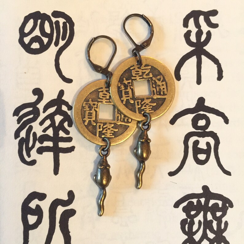 May include: A pair of gold-tone earrings featuring a Chinese coin charm with the characters "福" and "財" and a dangling mouse charm.