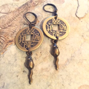 May include: A pair of gold-tone earrings featuring a Chinese coin charm with the characters "fu" and "lu" and a dangling mouse charm.