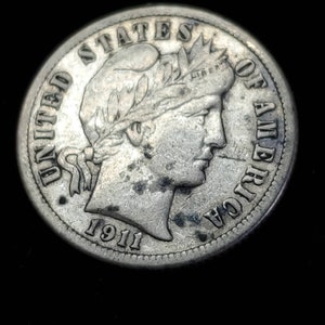 Peut inclure: Une pi&egrave;ce de monnaie am&eacute;ricaine en argent de dix cents avec l'ann&eacute;e 1911 inscrite en bas. La pi&egrave;ce repr&eacute;sente un portrait de la Libert&eacute; avec une couronne de laurier sur la t&ecirc;te.