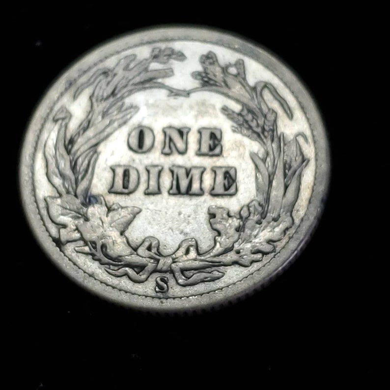 Peut inclure: Une pi&egrave;ce de monnaie am&eacute;ricaine en argent d'une valeur de dix cents avec l'inscription "ONE DIME" entour&eacute;e d'une couronne de feuilles. La pi&egrave;ce porte une petite marque de fabrique "S".