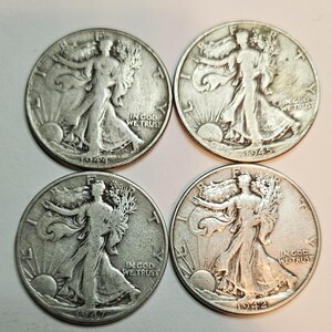 May include: Four silver Walking Liberty half dollar coins from 1942, 1944, 1945, and 1947. The coins feature the image of Liberty walking with a torch and an olive branch.