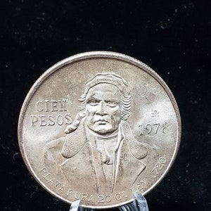 Op de afbeelding: Een zilveren munt met een portret van een man, met de tekst "CIEN PESOS" en het jaartal "1978". De munt heeft ook de tekst "PLATA PURA 20 G. LEY 720".