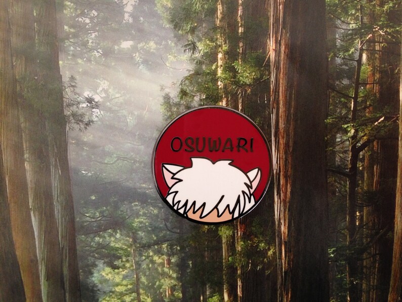 Puede incluir: Un pin de esmalte rojo y blanco con la cabeza de un personaje de dibujos animados y el texto "OSUWARI" sobre un fondo rojo.
