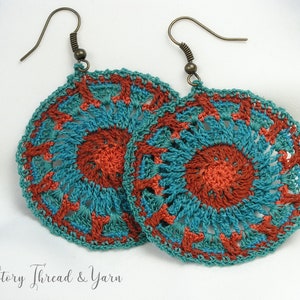 May include: A pair of crocheted earrings with a teal and orange mandala design. The earrings are made with a delicate, intricate pattern and have a bohemian style.