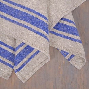 May include: A folded linen kitchen towel with blue stripes on a wooden surface.