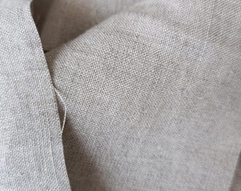 Könnte beinhalten: Nahaufnahme eines Stücks hellgrauen Leinenstoffs mit einer strukturierten Webart. Der Stoff ist gefaltet und zerknittert, wodurch die natürliche Textur des Materials sichtbar wird.