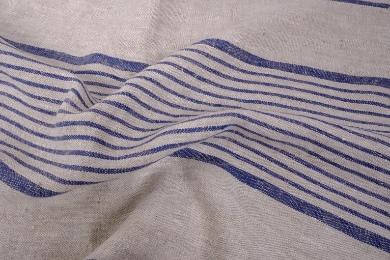 May include: A close-up of a piece of fabric with blue and white stripes. The fabric is wrinkled and has a natural texture.