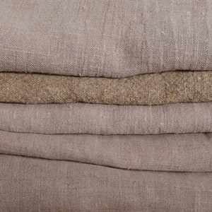 May include: A stack of five beige and brown linen fabric swatches. The fabric is woven with a textured pattern.