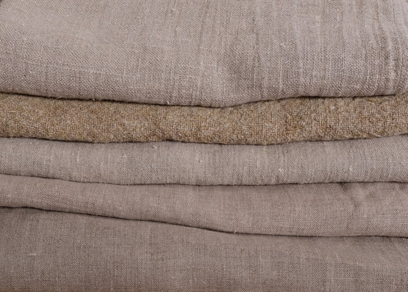 May include: A stack of five beige and brown linen fabric swatches. The fabric is woven with a textured pattern.