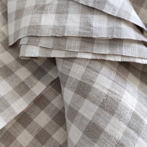 May include: A close-up of a stack of brown and white gingham fabric. The fabric is folded in a way that shows the pattern of the gingham.