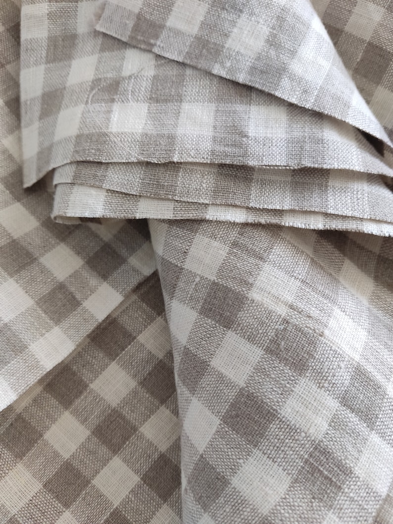 May include: A close-up of a stack of brown and white gingham fabric. The fabric is folded in a way that shows the pattern of the gingham.