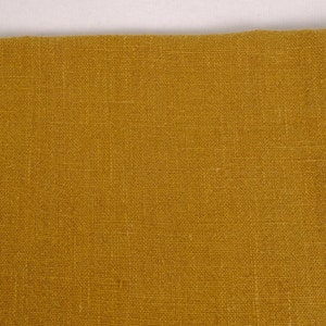 May include: A close-up of a piece of mustard yellow fabric with a woven texture.