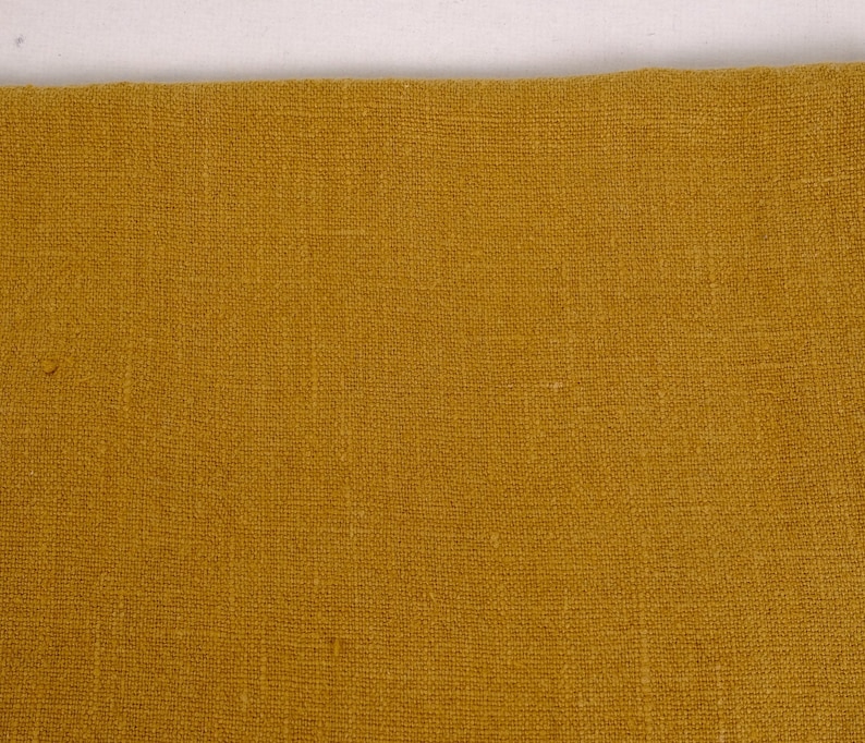May include: A close-up of a piece of mustard yellow fabric with a woven texture.
