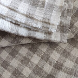 May include: A close-up of a folded piece of fabric with a brown and white gingham pattern. The fabric is soft and textured, with a slightly frayed edge.