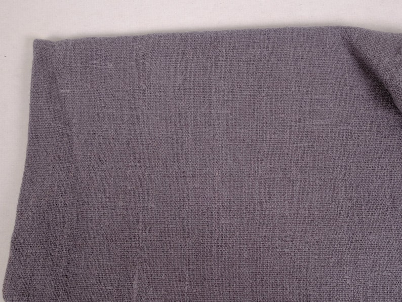 May include: A close-up of a piece of gray fabric with a textured weave. The fabric has a subtle sheen and a slightly rough feel.