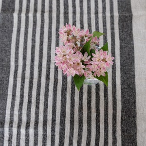 May include: A bouquet of pink flowers in a clear glass vase on a striped table runner.