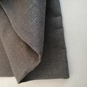 Puede incluir: Dos piezas de tela gris oscuro, una doblada sobre la otra. La tela tiene una textura tejida.