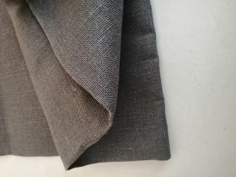 Puede incluir: Dos piezas de tela gris oscuro, una doblada sobre la otra. La tela tiene una textura tejida.