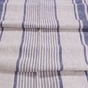 May include: A close-up of a linen fabric with blue and white stripes. The fabric is folded in thirds, showing the pattern.