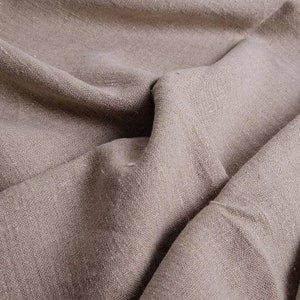 May include: Close-up of a textured, light brown fabric with a wrinkled surface. The fabric has a natural, linen-like appearance.