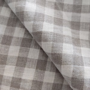 May include: A close-up of a white and gray gingham fabric. The fabric has a woven texture and is folded in half.