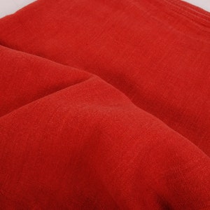 May include: A close-up of a red fabric with a textured surface. The fabric is folded in half and the folds create a soft, rounded shape.