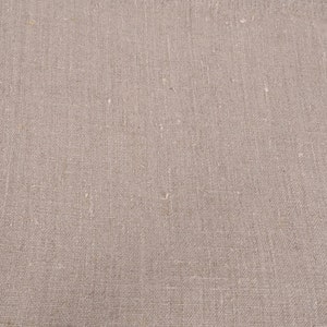 May include: Close-up of a plain, off-white, woven fabric with a subtle texture. The fabric has a slightly rough, natural feel.