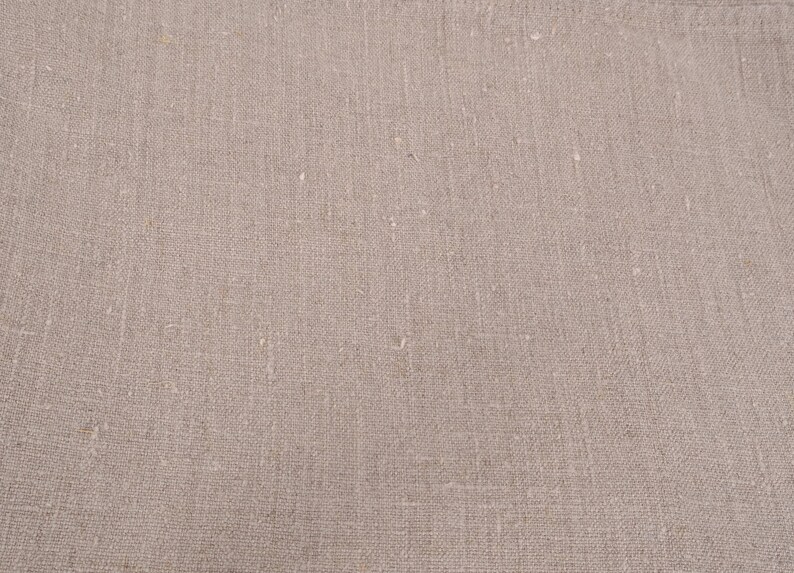 May include: Close-up of a plain, off-white, woven fabric with a subtle texture. The fabric has a slightly rough, natural feel.