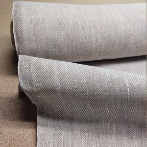 May include: A roll of light gray linen fabric with a subtle herringbone weave.