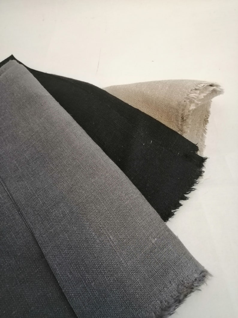 Puede incluir: Cuatro muestras de tela en diferentes tonos de gris, de claro a oscuro, con bordes deshilachados.