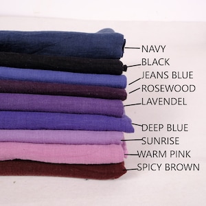 May include: A stack of ten fabric swatches in various shades of blue, purple, pink, and brown. The swatches are labelled with the following colours: Navy, Black, Jeans Blue, Rosewood, Lavendl, Deep Blue, Sunrise, Warm Pink, and Spicy Brown.
